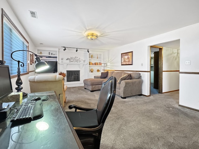 living room featuring built in shelves, track lighting, and carpet flooring