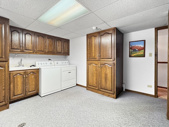 clothes washing area featuring cabinets, washer and dryer, sink, and light colored carpet