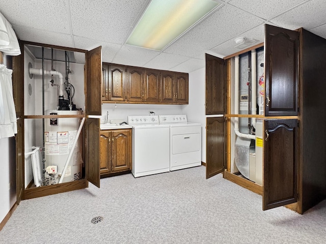 laundry area featuring water heater, washing machine and dryer, light colored carpet, and cabinets