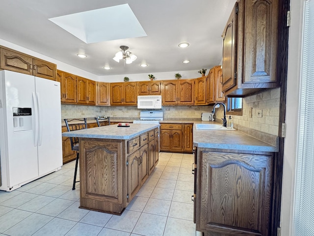 kitchen featuring sink, white appliances, a breakfast bar, a kitchen island, and light tile patterned flooring