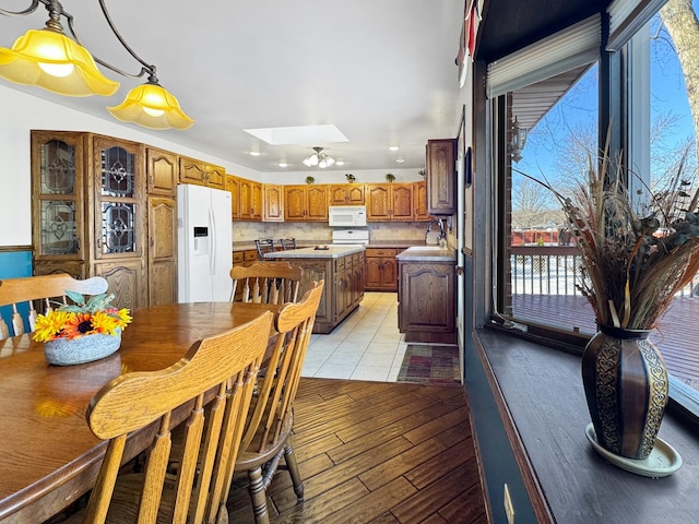 dining room featuring a skylight, sink, and light hardwood / wood-style flooring