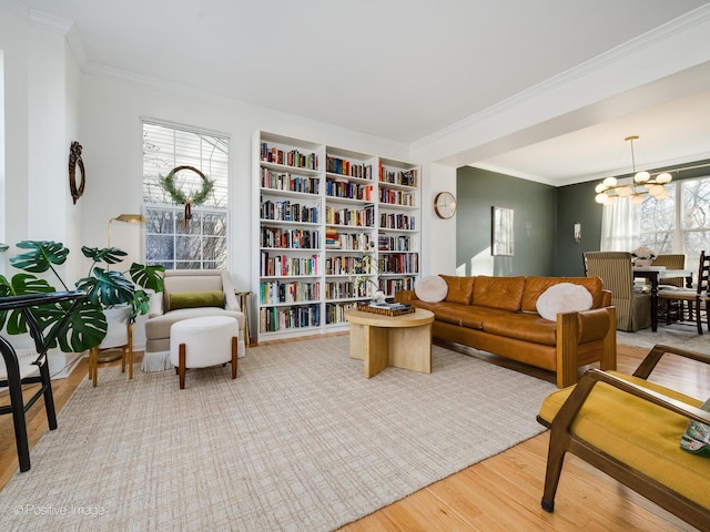 living room featuring a notable chandelier, ornamental molding, and light wood-type flooring