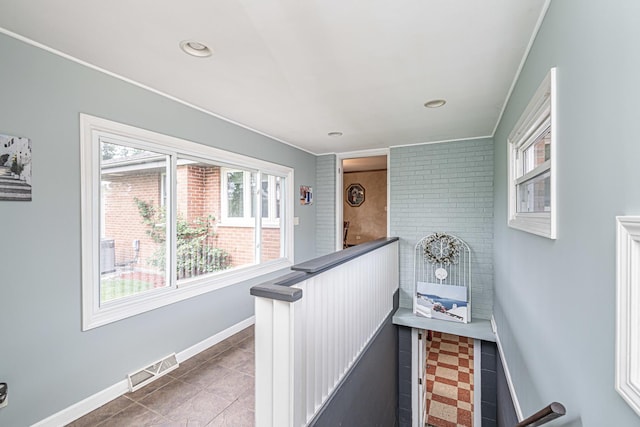 corridor with a healthy amount of sunlight, tile patterned flooring, baseboards, and visible vents