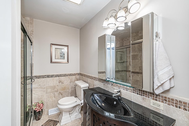full bath with tile walls, toilet, vanity, a shower stall, and wainscoting
