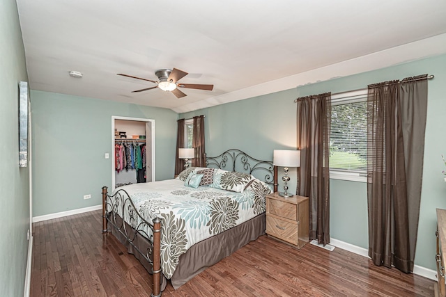 bedroom with baseboards, a spacious closet, a closet, and wood finished floors