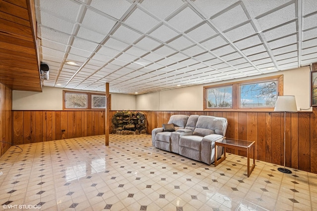 below grade area featuring a wainscoted wall, tile patterned floors, plenty of natural light, and wood walls