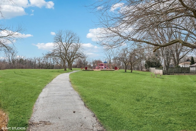 view of home's community with playground community, a yard, and fence