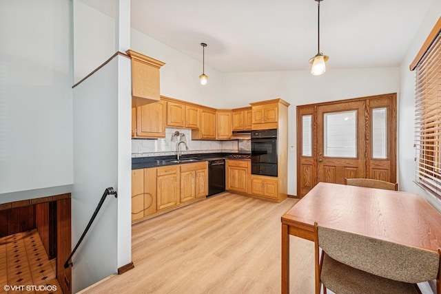 kitchen featuring a sink, a warming drawer, black appliances, light wood finished floors, and dark countertops