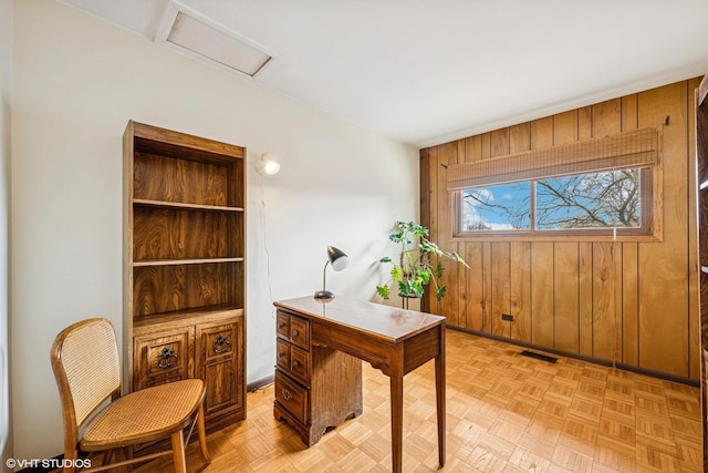 office area with attic access, wooden walls, and visible vents