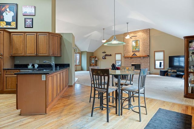 kitchen with plenty of natural light, decorative light fixtures, light hardwood / wood-style floors, and a brick fireplace