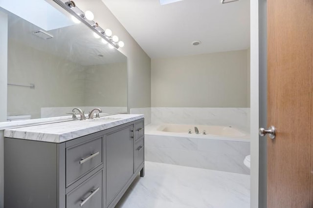 bathroom featuring a relaxing tiled tub and vanity