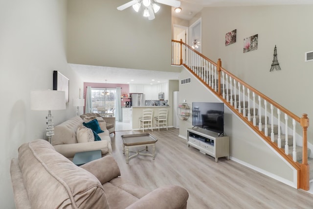 living room with ceiling fan, high vaulted ceiling, and light hardwood / wood-style flooring