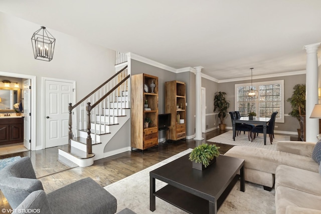 living room featuring ornate columns, hardwood / wood-style floors, sink, a chandelier, and crown molding