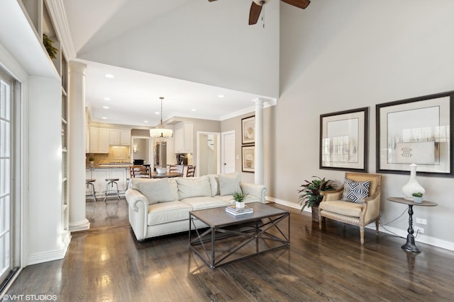 living room with dark hardwood / wood-style floors, high vaulted ceiling, decorative columns, ceiling fan, and crown molding