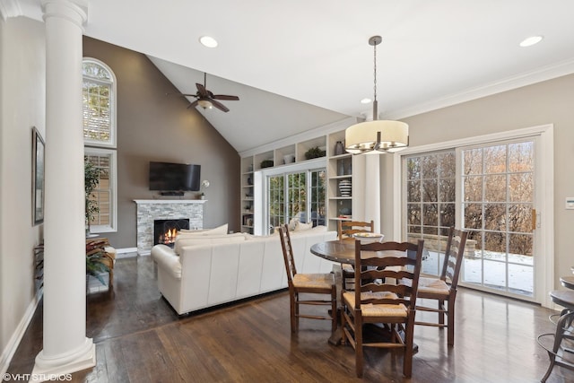 dining area featuring dark hardwood / wood-style floors, plenty of natural light, a stone fireplace, and decorative columns