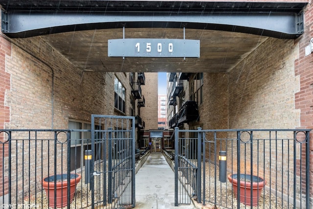 view of exterior entry featuring brick siding and fence