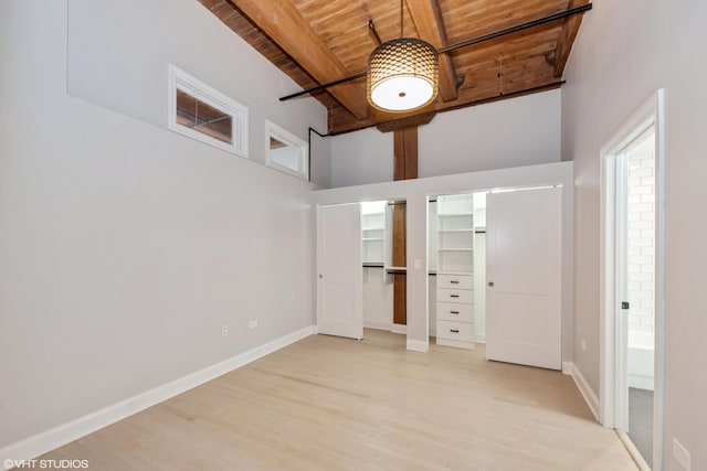 unfurnished bedroom featuring light wood finished floors, beamed ceiling, wooden ceiling, and baseboards