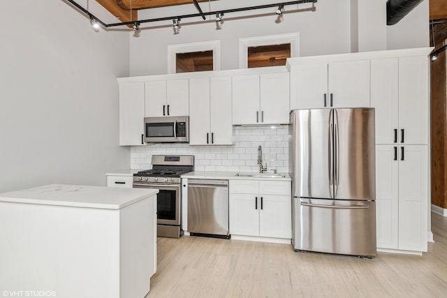 kitchen featuring a sink, stainless steel appliances, light countertops, white cabinetry, and backsplash