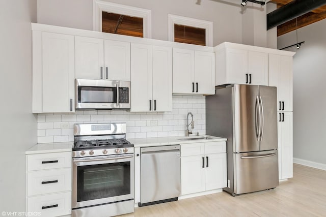 kitchen featuring a sink, tasteful backsplash, stainless steel appliances, white cabinets, and light countertops