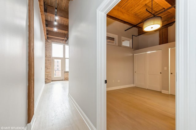 hallway with beam ceiling, wood finished floors, wood ceiling, and baseboards