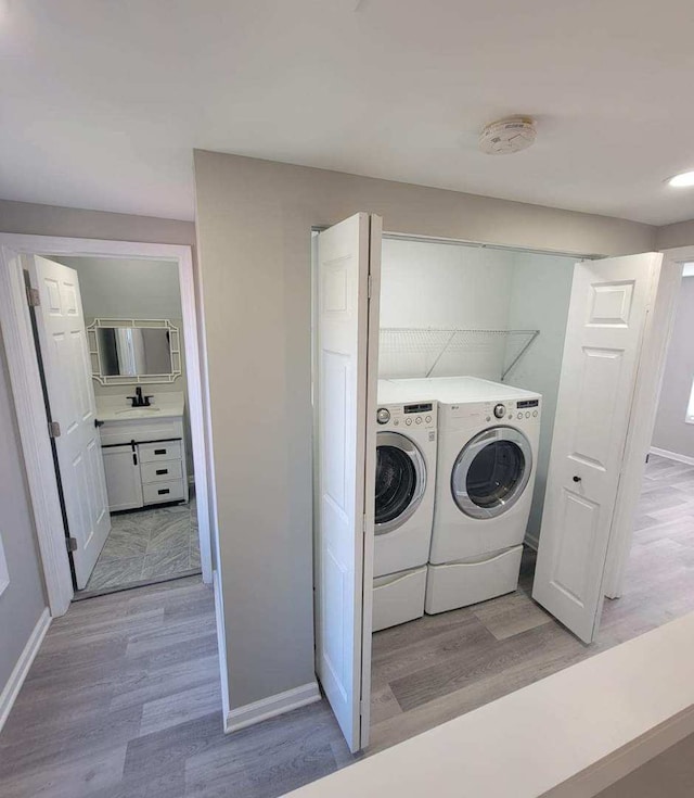 laundry room featuring sink, separate washer and dryer, and light hardwood / wood-style floors