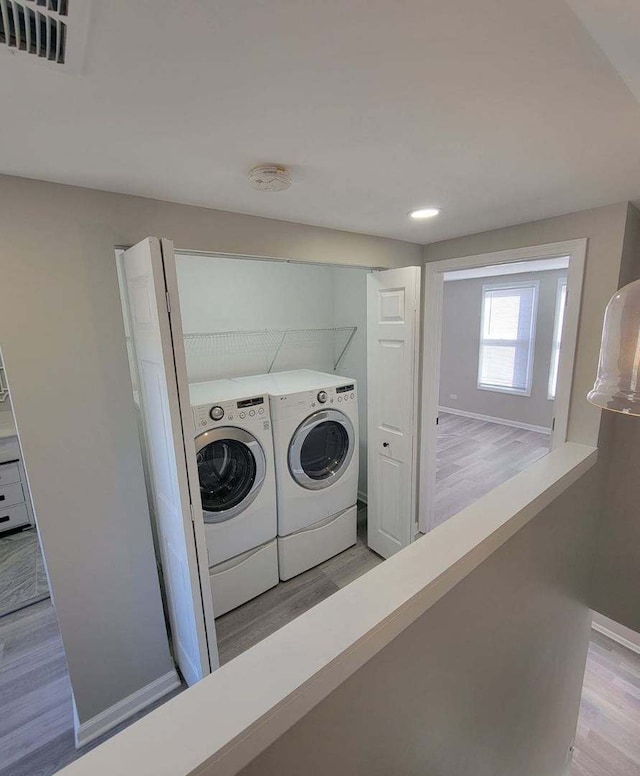 laundry room with independent washer and dryer and light wood-type flooring