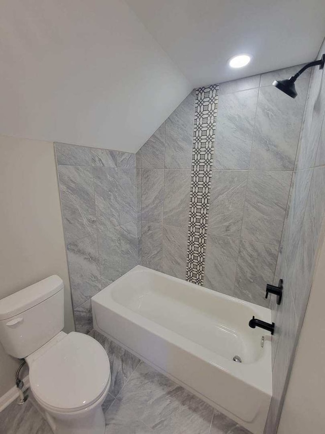 bathroom with tiled shower / bath, vaulted ceiling, and toilet