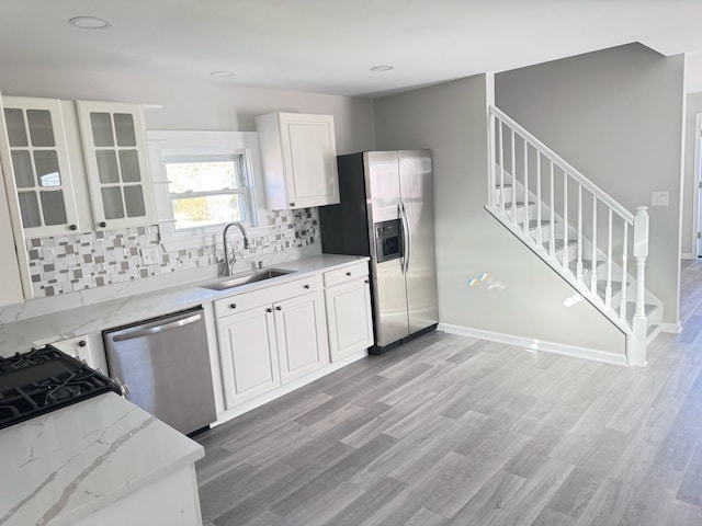 kitchen with light stone countertops, appliances with stainless steel finishes, sink, and white cabinets