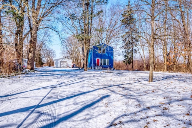 snowy yard with a detached garage and an outbuilding