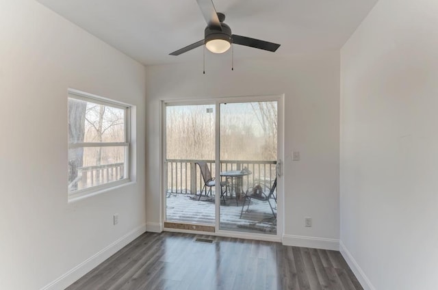 unfurnished room featuring dark wood-style floors, visible vents, and baseboards