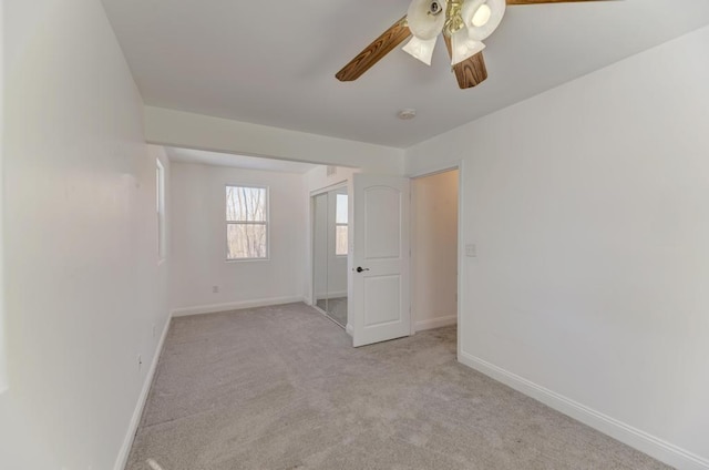 spare room with light colored carpet, ceiling fan, and baseboards