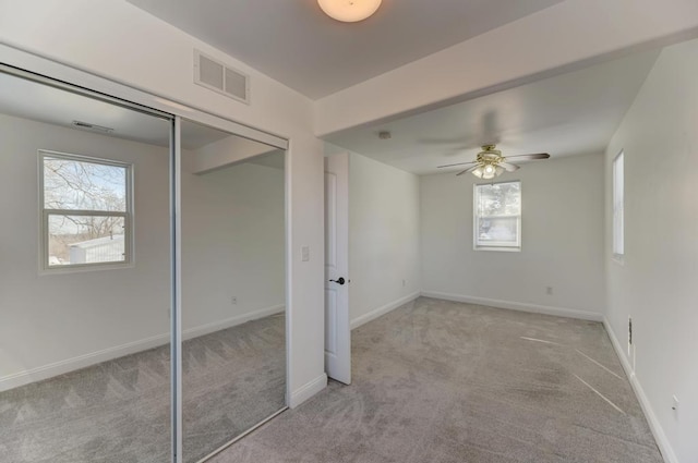 interior space with light carpet, baseboards, visible vents, and a ceiling fan