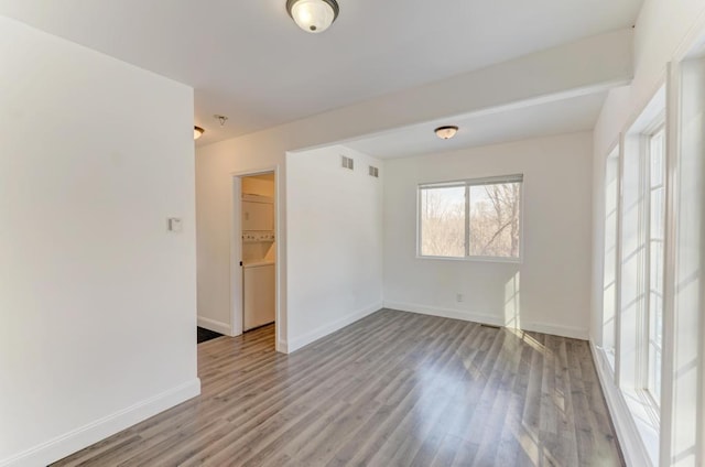 empty room featuring light wood finished floors, visible vents, and baseboards