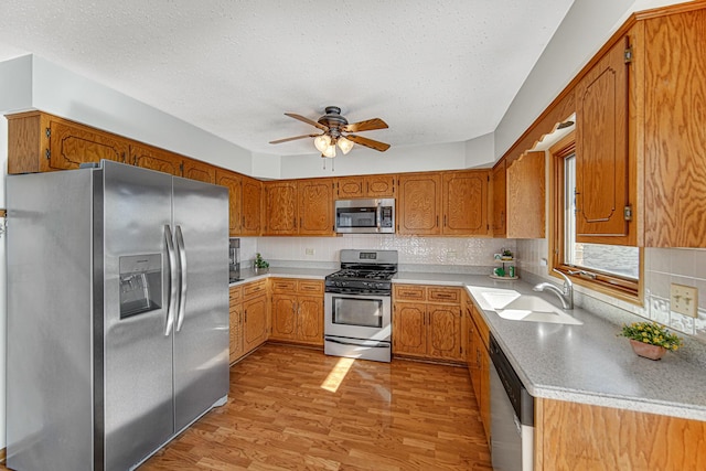 kitchen with light hardwood / wood-style flooring, sink, a textured ceiling, stainless steel appliances, and tasteful backsplash