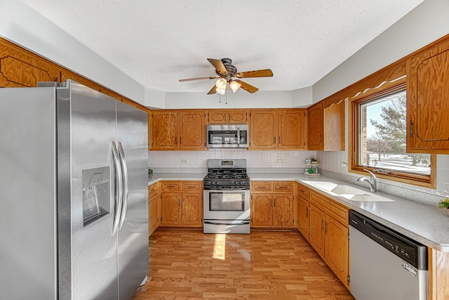 kitchen with tasteful backsplash, stainless steel appliances, ceiling fan, light hardwood / wood-style floors, and sink