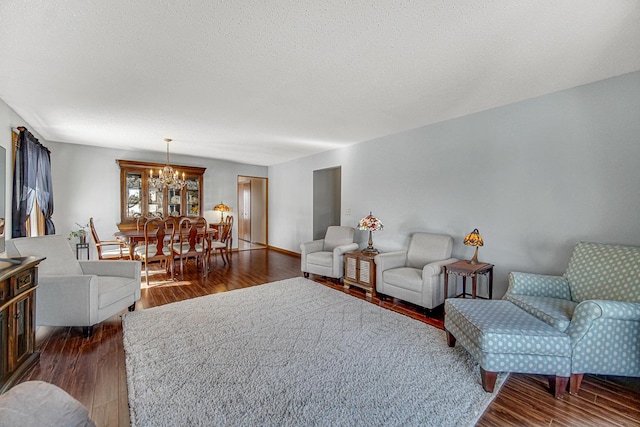 living room with a textured ceiling, dark wood-type flooring, and a chandelier