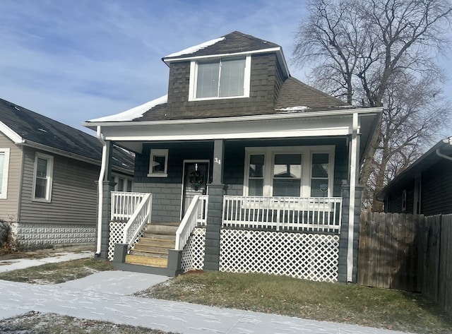 view of front of house featuring covered porch, roof with shingles, and fence