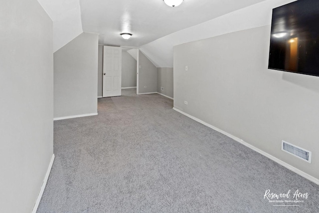 bonus room with vaulted ceiling and light colored carpet