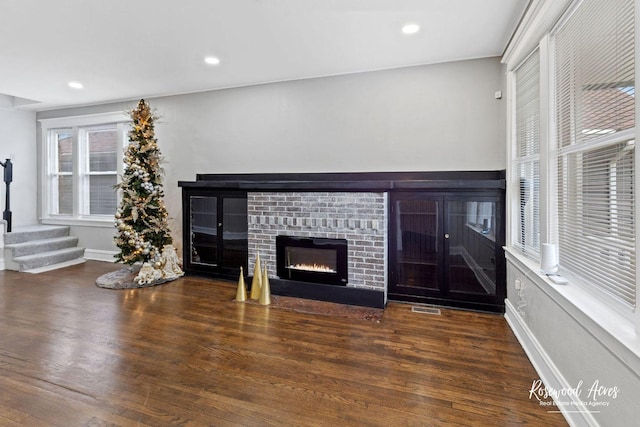 unfurnished living room featuring dark hardwood / wood-style flooring and a brick fireplace