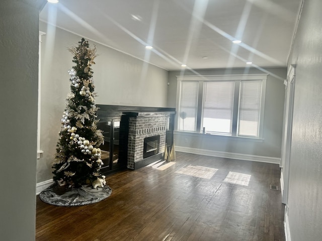 unfurnished living room featuring a brick fireplace and dark hardwood / wood-style flooring