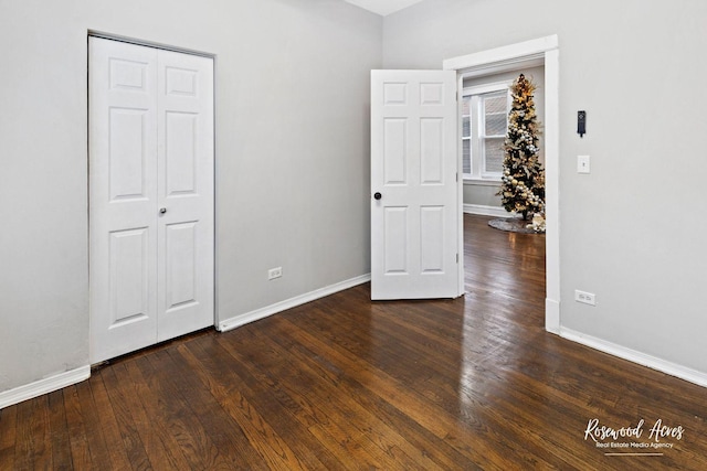 unfurnished bedroom with dark hardwood / wood-style flooring and a closet