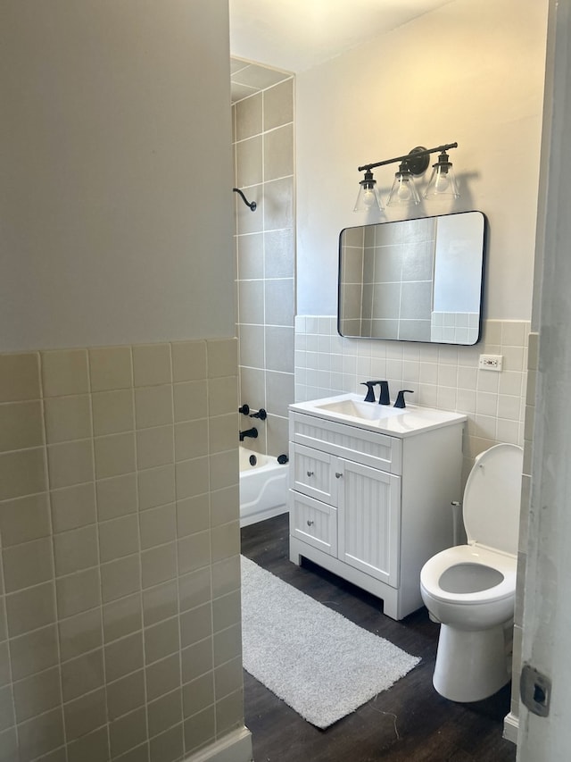 full bathroom featuring tile walls, vanity, tiled shower / bath combo, and wood-type flooring