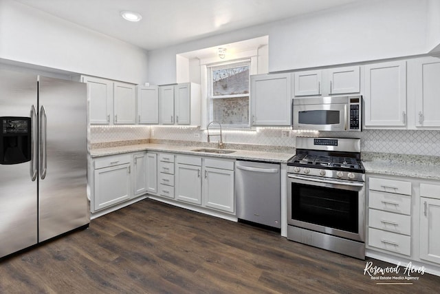 kitchen with dark hardwood / wood-style floors, sink, white cabinets, light stone counters, and stainless steel appliances