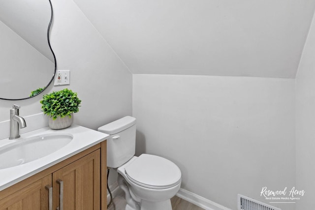 bathroom featuring lofted ceiling, vanity, and toilet