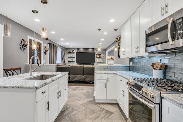 kitchen featuring a kitchen island with sink, appliances with stainless steel finishes, sink, and white cabinets