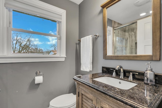 bathroom featuring vanity, an enclosed shower, and toilet