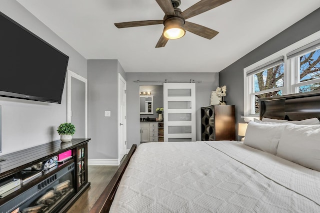 bedroom featuring dark wood-type flooring, a barn door, and ceiling fan