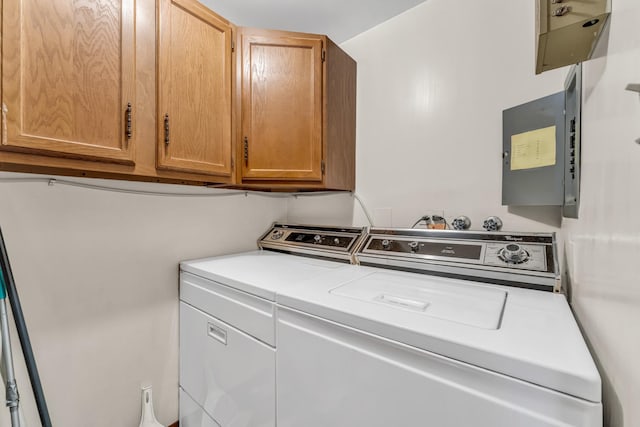 laundry area featuring cabinets, washing machine and clothes dryer, and electric panel