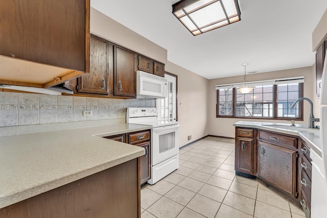 kitchen featuring light tile patterned flooring, dark brown cabinetry, decorative light fixtures, white appliances, and decorative backsplash