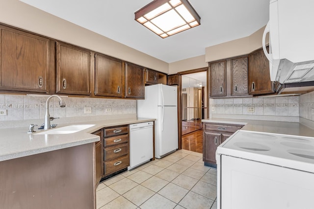 kitchen with dark brown cabinets, sink, white appliances, and decorative backsplash